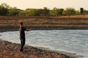 man in sneakers trying to fish | Hooville Ranch hunting and lodging