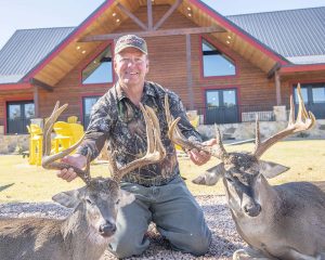 famous hunter holds two deer antlers | Hooville Ranch hunting and lodging